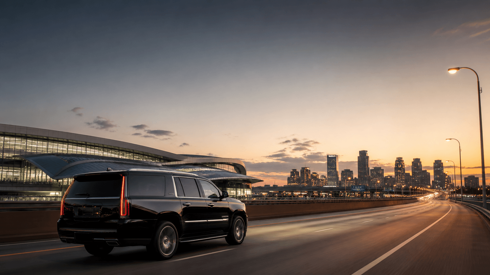 Black Dominion SUV traveling from the airport toward the city at dusk